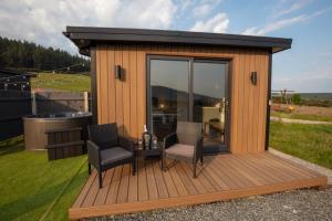 OAKWOOD GLAMPING Mourne Mountains في Moyad: كابينة بها كرسيين وطاولة على السطح