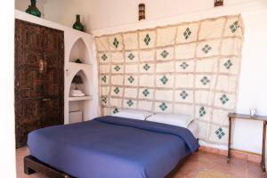 a bedroom with a blue bed and a wall at Riad Ben Youssef in Marrakech