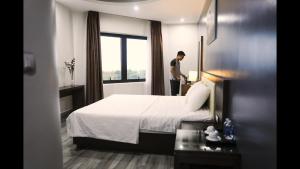 a man standing in a hotel room with a bed at Sen Biển Hotel FLC Sầm Sơn in Sầm Sơn +30 photos