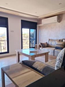 uma sala de estar com um sofá e uma mesa em Appartement Sable Rose em Al Hoceïma