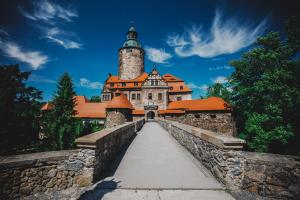 a castle with a clock tower on a bridge at Zamek Czocha in Leśna