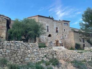 un antiguo edificio de piedra con una pared de piedra en Castell de l'Aguda, en Torá de Rulbregos