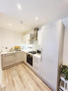a kitchen with white cabinets and a large white refrigerator at The Seaside Maisonette. Free Parking/Close To Town in Bournemouth