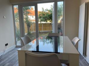 uma sala de jantar com uma mesa de vidro e cadeiras em Modern 4-bedroom entire house with Garden em Uxbridge