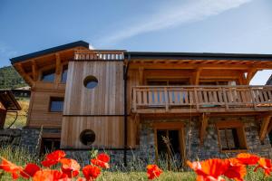 a log cabin with a deck and red flowers at Chalet Holtanna Mountain Voyages in Montriond