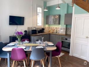 cocina con mesa de comedor y sillas moradas en La Rose des Sables en Trouville-sur-Mer