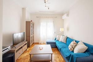 a living room with a blue couch and a tv at Quiet Central apt in picturesque Pagrati in Athens