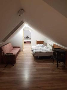 a attic room with a bed and a couch at Zajazd Ponikiew - Noclegi Wadowice in Wadowice