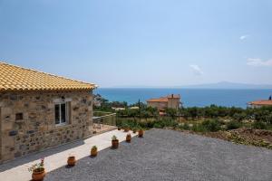 ein Steinhaus mit Topfpflanzen auf einer Einfahrt in der Unterkunft Lithino Rooms Kalamata in Kalamata
