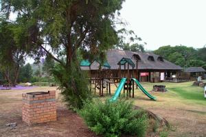 a playground in front of a building with a tree at Gooderson Leisure Natal Spa Self Catering and Timeshare Resort in Paulpietersburg