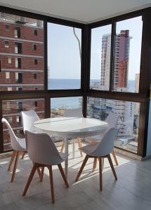 uma mesa e cadeiras num quarto com uma grande janela em Mediterraneo 43 em Benidorm
