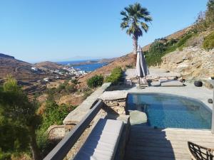 a villa with a swimming pool and a palm tree at Kydippi Kea Villa in Korissia