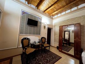 a room with a table and chairs and a mirror at Grand Emir Residence in Bukhara