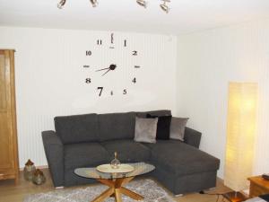 a living room with a couch and a clock on the wall at Ferienwohnung Am Stadtrand in Dwasieden