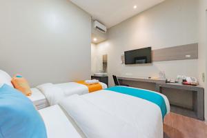 a hotel room with two beds and a television at Sans Hotel Berau Square in Tanjungredep
