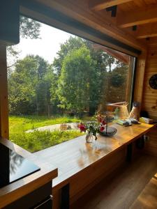 ein großes Fenster in einem Zimmer mit einem Holztisch in der Unterkunft MoodySun Studio, remote tiny home in Comarnic