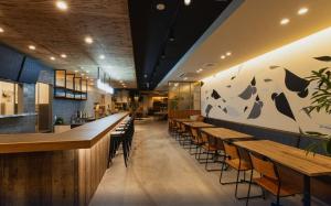 Mash Cafe & Bed NAGANO في ناغانو: وجود بار بطاولات وكراسي خشبية في المطعم