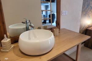 uma casa de banho com um lavatório branco e um espelho. em La Maisonnette de l Espace Themis, piscine partagée em Saint-Germain-de-Salles