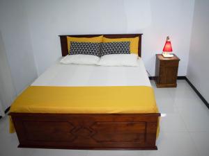 a bedroom with a large bed with yellow sheets and a lamp at pvc 2 in Hikkaduwa