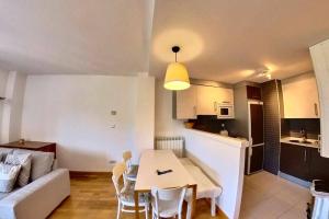 a kitchen and a living room with a table and chairs at Casa El Paco - tucasaenlospirineos in Sallent de Gállego