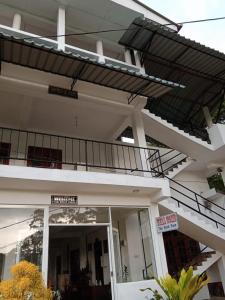 a white building with a balcony on top of it at The Rock Face in Ella