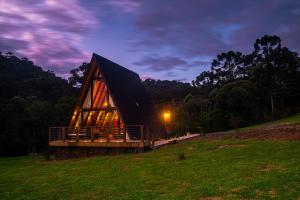 a large wooden cabin with a black roof in a field at Urutau Pousada in Urubici