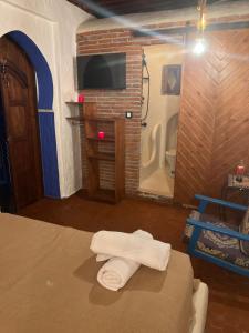 a bedroom with a bed and a television and towels at Riad Mauritania in Chefchaouene