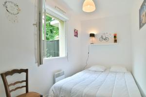 ein weißes Schlafzimmer mit einem Bett und einem Fenster in der Unterkunft Butterfly - Appartement avec jardin in Miniac-Morvan