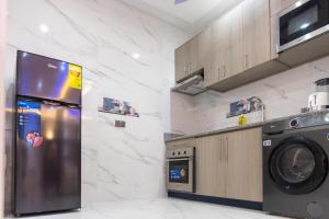 een keuken met een koelkast, een wasmachine en een droger bij Executive Studio Apartment, East Airport in Accra