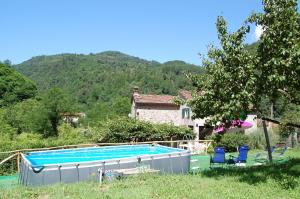 a swimming pool in front of a house with a mountain at Casa Millefiori in Bagni di Lucca
