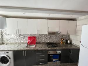 a kitchen with white cabinets and a redettel at Appartement de luxe, Tanagra Mall in Kenitra