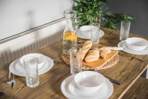 a wooden table with white plates and bread on it at Blackpool Abode - Coastel Suite Apartment in Blackpool