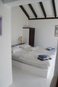 Una cama en una habitación blanca con sábanas blancas y libros. en Strandhaus, en Los Llanos de Aridane