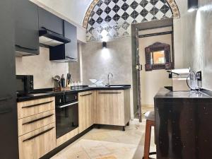 a kitchen with wooden cabinets and black appliances at The Cliff Appartment in Dar Mimoun Bey