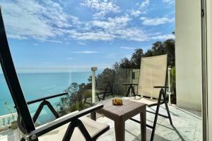 balcón con mesa, sillas y vistas al océano en The Cliff Appartment en Dar Mimoun Bey