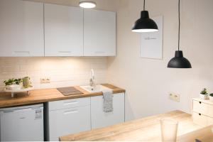 una cocina con armarios blancos y fregadero en Apartament Szczerbowskiego B, en Lublin