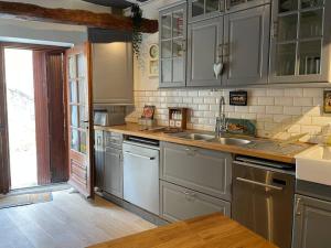 een keuken met grijze kasten en een wastafel bij Maison de village en pierre in Saint-Cyprien
