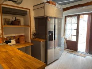 een keuken met een roestvrijstalen koelkast en een raam bij Maison de village en pierre in Saint-Cyprien