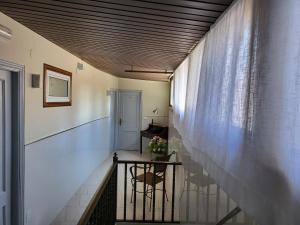a hallway with a staircase with a chair and a window at CASA MARUXA pensión in Pontevedra