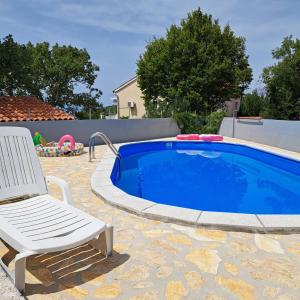 a chair sitting next to a swimming pool at Apartman Dadić in Malinska