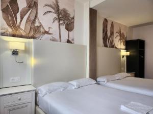 two beds in a hotel room with twoermottermott at HOTEL ROYAL Paris Ivry in Ivry-sur-Seine