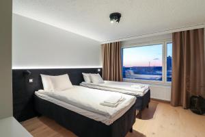 two beds in a room with a large window at Prime Penthouse Central - jacuzzi and sauna in Pori