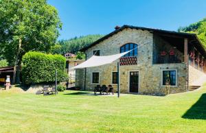 a stone house with a large yard in front of it at Agriturismo Poderino in Castiglione di Garfagnana