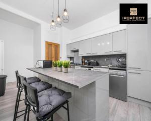 Glasgow Airport Luxury Apartment By Your Perferct Stay Short lets Glasgow في بيزلي: مطبخ مع كونتر كبير مع كرسيين للبار