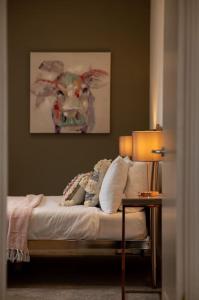 a bedroom with a bed with a cow painting on the wall at Luxury Barn Conversion with Hot Tub- 'Blackbird' in Ab Lench +8 photos