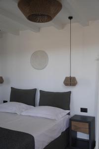 a bedroom with a bed with white sheets and a table at Azul Houses Kythnos in Kithnos