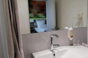 ein Badezimmer mit einem weißen Waschbecken und einem Spiegel in der Unterkunft Thermalhotel Kemper in Erwitte