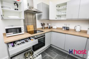a kitchen with white cabinets and a microwave at Host Liverpool - Chic family spot, near Anfield & centre in Liverpool