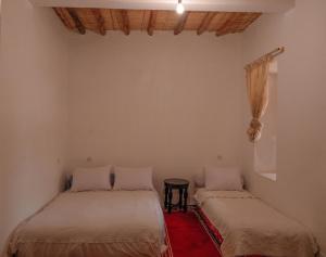 Zimmer mit 2 Betten und einem Tisch in der Unterkunft coooperative_ogandou_skoura in Skoura
