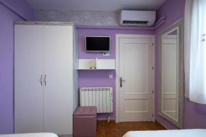 1 dormitorio con paredes moradas y TV en la pared en Casa Rural La Posada del 42, en Carrascalejo